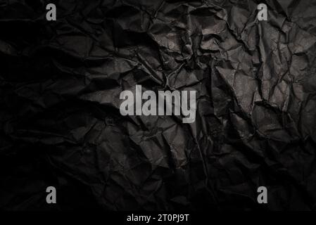 A sheet of black crumpled paper with folds and wrinkles. Dark paper texture Stock Photo