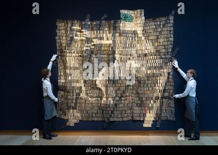 London, UK. 06th Oct, 2023. LONDON, UNITED KINGDOM - OCTOBER 06, 2023: Gallery staff members look at an artwork by El Anatsui, Warrior, 2015, estimate £700,000 - 1,000,000 during a photocall at Christie's auction house showcasing the highlights of 20th/21st Century Evening Sale in London, United Kingdom on October 06, 2023. (Photo by WIktor Szymanowicz/NurPhoto) Credit: NurPhoto SRL/Alamy Live News Stock Photo