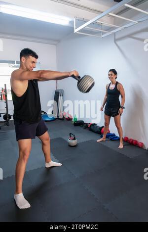 A gymnast is doing exercises with weights while his trainer watches and supervises him Stock Photo