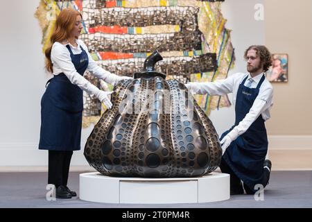 London, UK. 06th Oct, 2023. LONDON, UNITED KINGDOM - OCTOBER 06, 2023: Gallery staff members hold an artwork by Yayoi Kusama, Pumpkin (S), 2014, estimate £2,400,000 - 4,000,000, during a photocall at Sotheby's auction house showcasing the highlights of Frieze Week Sales in London, United Kingdom on October 06, 2023. The artworks will be on view at Sotheby's auction house between 7 and 11 October before being offered during The Now and Contemporary Evening auctions on October 12. (Photo by WIktor Szymanowicz/NurPhoto) Credit: NurPhoto SRL/Alamy Live News Stock Photo