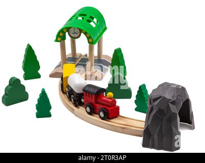 Children's toy train with two cars on a wooden railroad. Trees and green Christmas trees with tunnel and station complete the toy world. Stock Photo