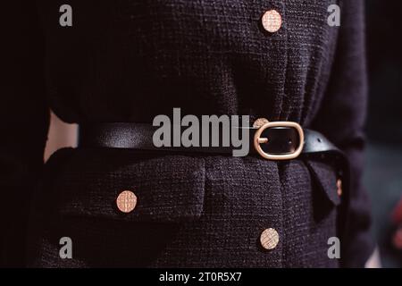 Fashion details of a classy black jacket, leather belt and golden buttons. Stock Photo