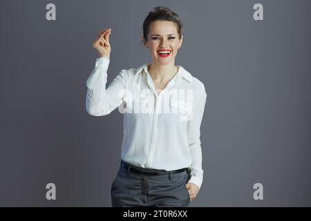 happy elegant woman worker in white blouse fingers snapping isolated on gray background. Stock Photo