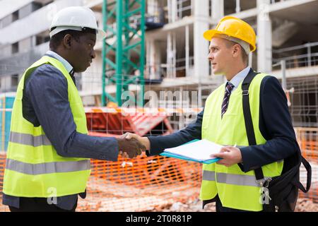 Two engineers concluding agreement and shaking hands Stock Photo
