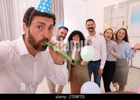 Coworkers taking selfie during office party indoors Stock Photo