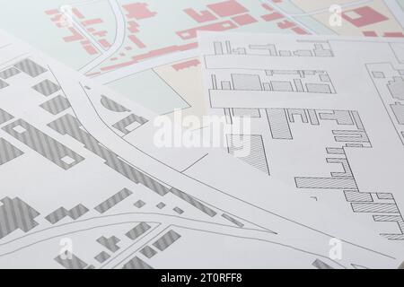 Many different cadastral maps of territory with buildings as background, closeup Stock Photo