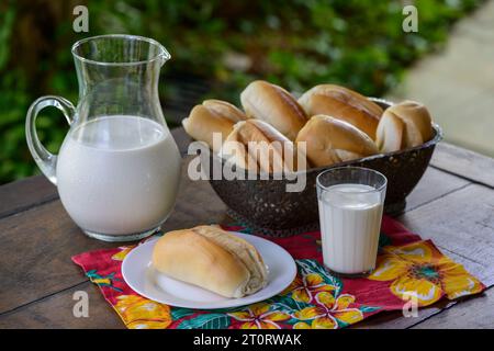 Bread in a basket and milk in a glass jug on a wooden table. Stock Photo