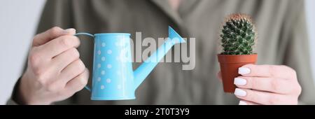 Woman holds watering can and decorative cactus in hands Stock Photo