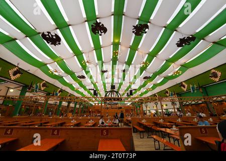 Munich, Germany, EU - September 18, 2023. Oktoberfest Munich Beer Tent interior with decorations, people drinking, eating in dirndls and lederhosen. Stock Photo