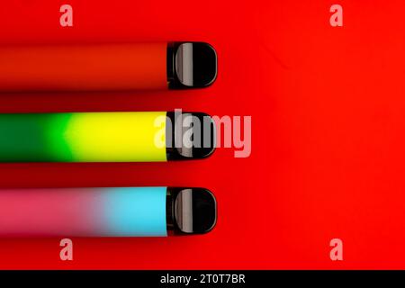 Disposable electronic cigarettes on red background close up Stock Photo