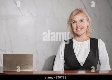 Woman receptionist smiles to customer at front desk Stock Photo