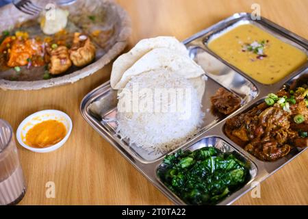 Chicken daal baht power (rice, spinach, lentil, pickle & chicken curry) served on a stainless steel tray at a Nepalese restaurant in Sydney Stock Photo