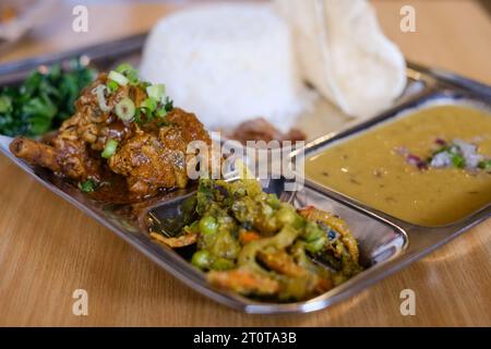 Chicken daal baht power (rice, spinach, lentil, pickle & chicken curry) served on a stainless steel tray at a Nepalese restaurant in Sydney Stock Photo