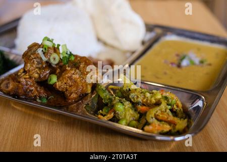 Chicken daal baht power (rice, spinach, lentil, pickle & chicken curry) served on a stainless steel tray at a Nepalese restaurant in Sydney Stock Photo