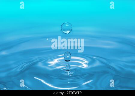 Clear aqua water droplet splashing in concentric circles, capturing refreshing purity. Stock Photo