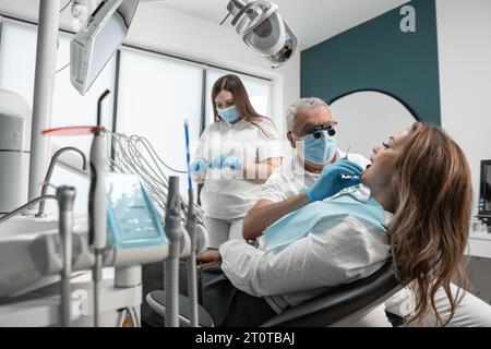 At the dental treatment center, there is a team of professionals who work to improve the patient's smile. Woman in dental chair receiving professional Stock Photo