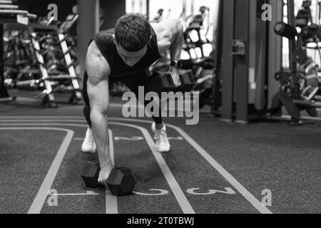 Athletic man doing dumbbell plank row in fitness gym. Fitness gym training. Fitness strength workout Stock Photo