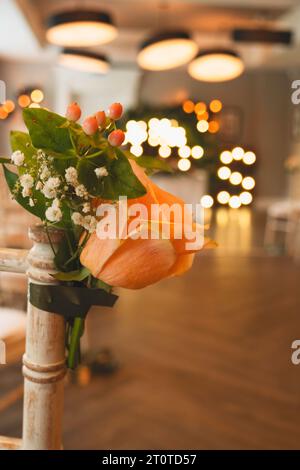 Wedding chair flowers showing the wedding lights and alter in the background Stock Photo
