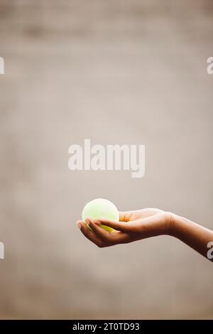 Close up of a black female tennis player holding a yellow tennis ball. Tennis player catching a ball with one hand while playing a match. Stock Photo