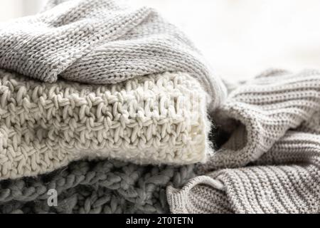 Close up of folded knitted items of grey color on a light background. Stock Photo