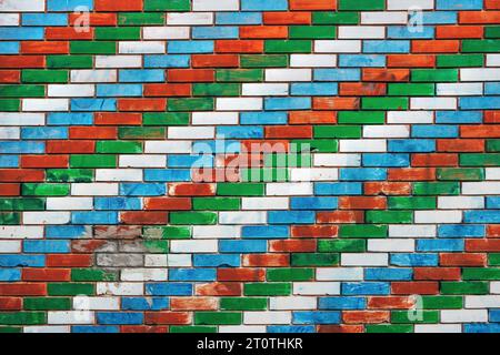 Colorful brick wall with diagonal pattern with white, blue, red and green colors, worn facade Stock Photo
