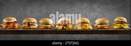 Assortment of different types of burgers on long wooden board Stock Photo