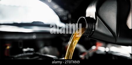 mechanic pouring motor oil from bottle into engine at car repair shop. banner with copy space Stock Photo