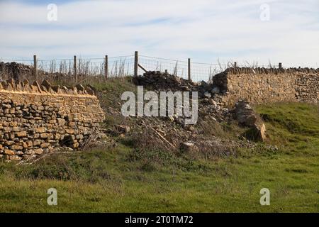 A beautiful old dry stone wall recently repaired now falling down due to unstable soil probably caused by excess waterfall and dryness. Stock Photo