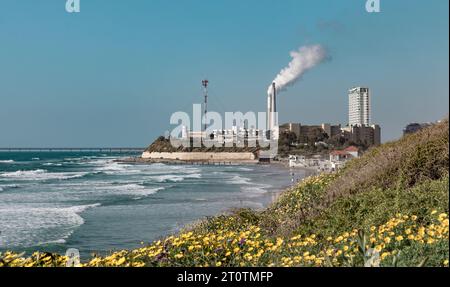 Gador Reserve Beach, Hadera, Israel, April 12; A view of the chimneys with smoke in the sky. An industrial zone emerges behind Flowers Hill Stock Photo