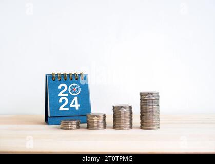 2024 new year target goal and success, savings, business investment and financial concepts. Coin stack as a growth graph with up arrows near 2024 desk Stock Photo