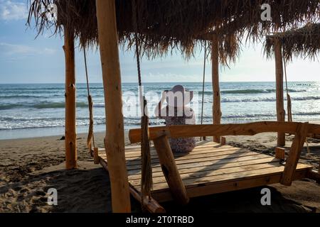Woman in hat on hanging bed on adriatic seashore Stock Photo