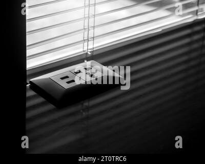 Black dual desk-mounted USB plugs and sockets on dark marble table near the window with louver, with copy space. Business technology concept. Outlet p Stock Photo