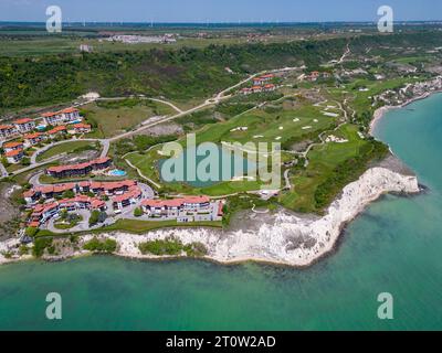 Aerial view of the golf course stretches out beneath, its lush green fairways complementing the breathtaking coastal panorama. Among the picturesque l Stock Photo