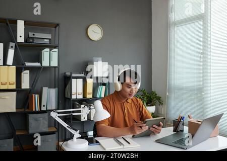 Young Asian developer working on tablet computer in his home office Stock Photo