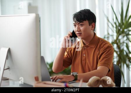 Portrait of concerned developer calling coworker asking to fix bugs in released project Stock Photo