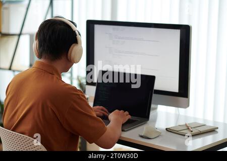 Developer wearing headphones when testing new software on laptop Stock Photo