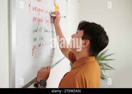 Developer writing programming code on whiteboard when trying to solve problem Stock Photo