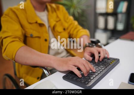 Closeup image of man with disability working on computer in office, answering e-mails and coding Stock Photo