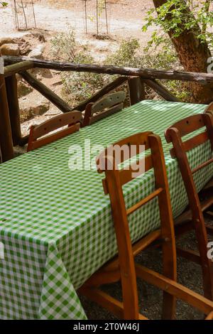 Geometric green checkered table runner on a picnic table and wooden chairs at a restaurant outdoors in nature Stock Photo