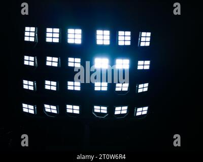 A close-up of stadium floodlights, illuminating the field. Powerful beams of light pierce the darkness, creating a sense of energy and excitement. Stock Photo