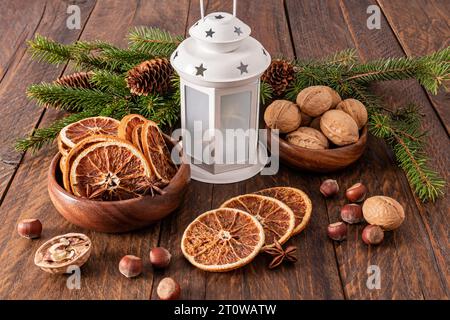 Festive Christmas arrangement with dried orange slices in wooden bowl, walnuts, white Christmas lantern. Rustic style Stock Photo