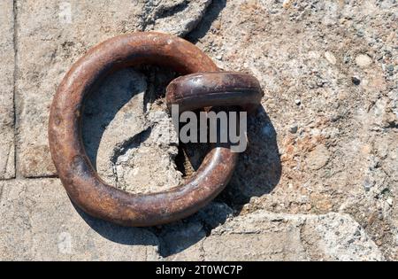Rusty old mooring loop on textured stone background. Top view. Stock Photo