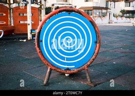 Blue and white optical spiral illusion or swirl effect on a metal board in a playground. Stock Photo