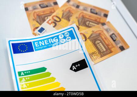 Augsburg, Bavaria, Germany - 9 September 2023: Energy label for electrical household appliances next to euro cash bills *** Energielabel für Elektro Haushaltsgeräte neben Euro Bargeld Scheinen Stock Photo