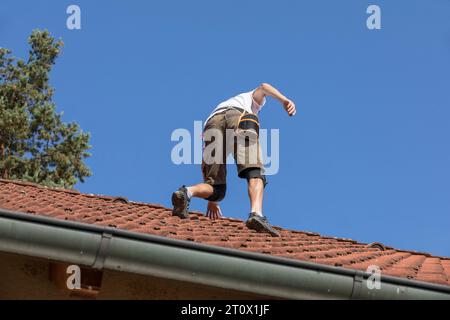 A worker prepares the roof for the installation of solar panels, red bags on the roof of the house ready for photovoltaic installations, installation Stock Photo