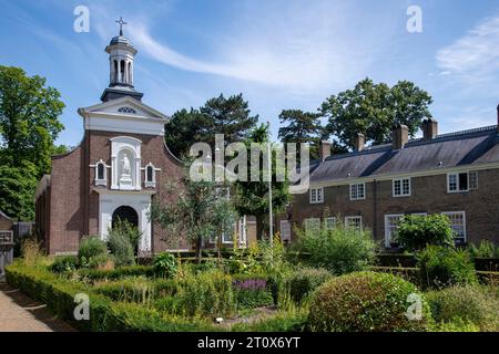 Courtyard of the beguinage (Begijnhof) in Breda, the Netherlands with herb garden and surrounded by 29 small houses and Catharina churck in background Stock Photo