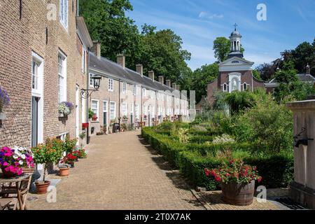 Courtyard of the beguinage (Begijnhof) in Breda, the Netherlands with herb garden and surrounded by 29 small houses and Catharina churck in background Stock Photo