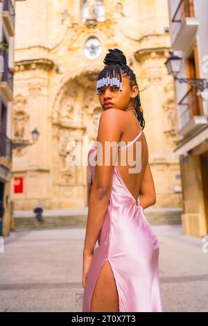 Dominican ethnic girl with braids with a beautiful pink dress. Fashion enjoying summer in a beautiful church of the city Stock Photo