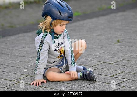 Boy with helmet, 5 years, sitting on floor, sad, Stuttgart, Baden-Wuerttemberg, Germany Stock Photo
