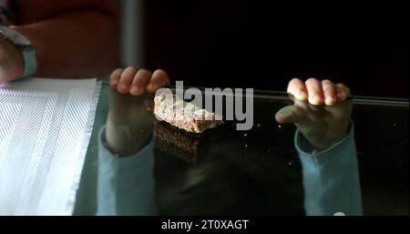 Child snacking bread and butter. Baby boy leaning on glass table grabbing food Stock Photo